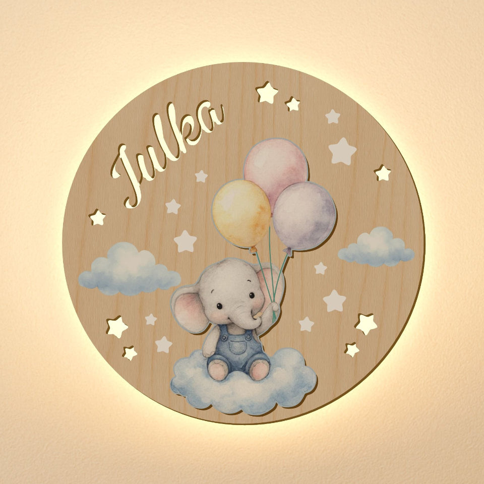 Wooden circular plaque with an elephant holding balloons and the name 'Julka' on a beige background.