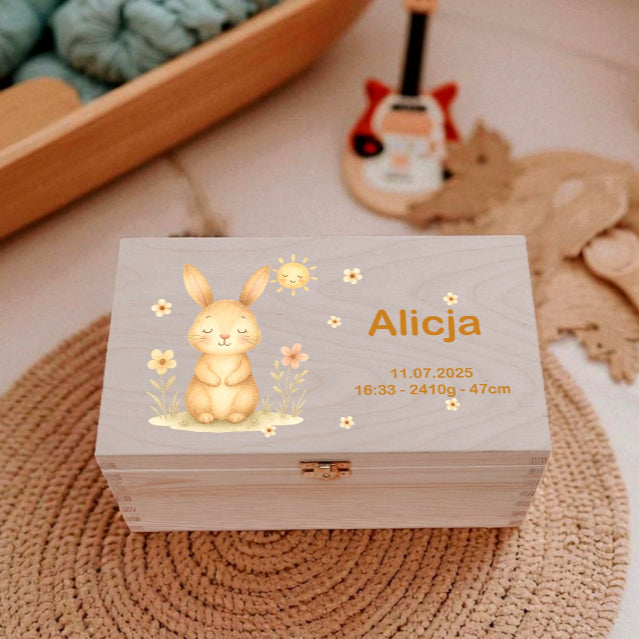 Wooden box with a rabbit design and personalized text on a textured surface.