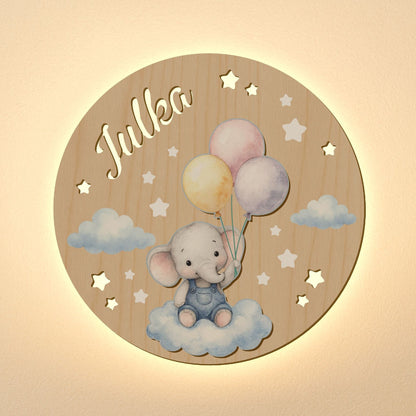 Wooden circular plaque with an elephant holding balloons and the name 'Julka' on a beige background.