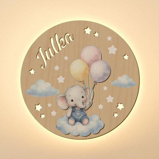 Wooden circular plaque with an elephant holding balloons and the name 'Julka' on a beige background.
