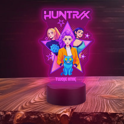 Decorative lamp with 'Huntrix' branding on a wooden surface