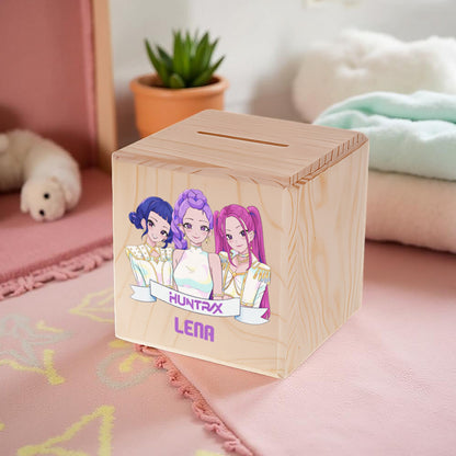 Wooden money box with cartoon characters and names on a pink surface