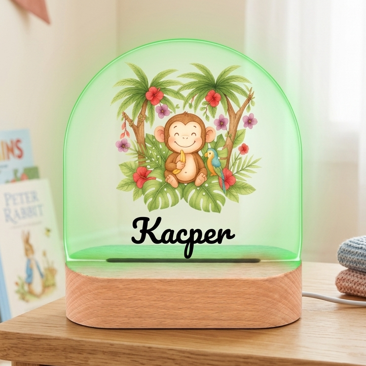 Decorative night light with a monkey design on a wooden surface, surrounded by books and toys.