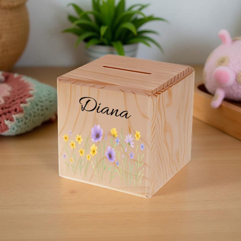 Wooden money box with floral design and 'Diana' engraving on a wooden surface.