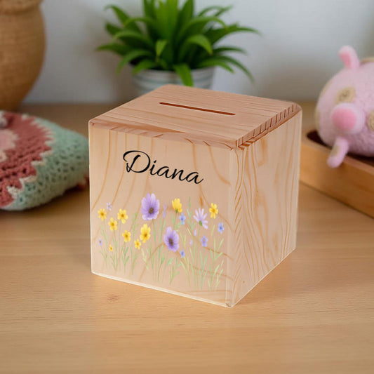 Wooden money box with floral design and 'Diana' engraving on a wooden surface.