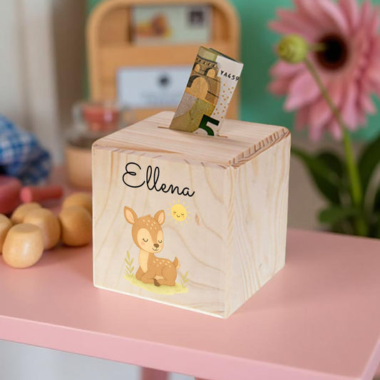 Wooden money box with a deer design and the name 'Ellena' on a pink surface.