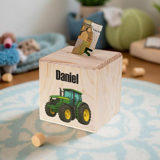 Wooden piggy bank with a tractor design and the name 'Daniel' on a carpeted floor.