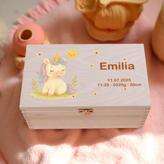 Wooden box with unicorn illustration and text on a pink surface with decorative items.