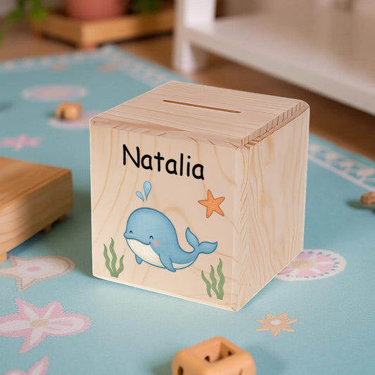 Wooden block with a whale design and 'Natalia' engraved, on a colorful play mat.